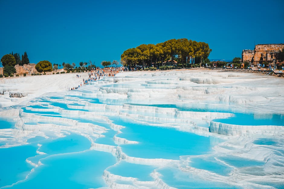 Stunning view of Pamukkale's turquoise thermal pools and terraces on a sunny day in Denizli, Türkiye.