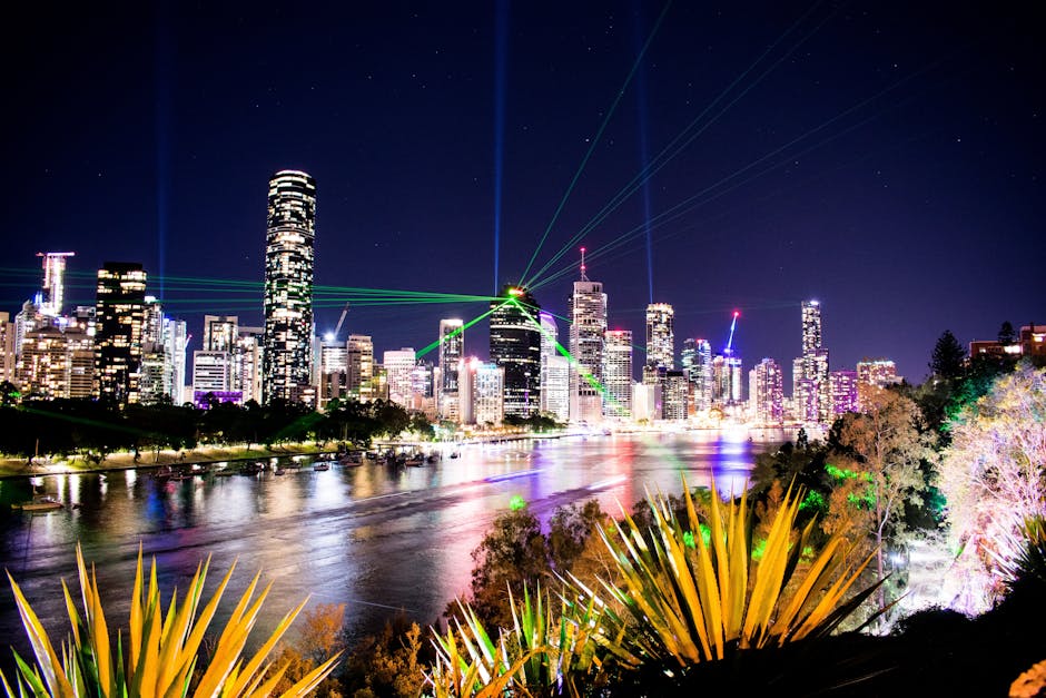 A dazzling view of Brisbane's skyline illuminated with colorful lights and reflections on the water at night.