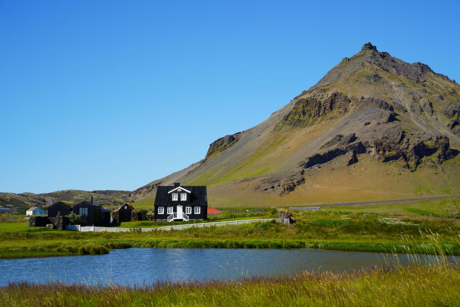 Charming village houses beneath a striking mountain in Iceland with clear blue skies.