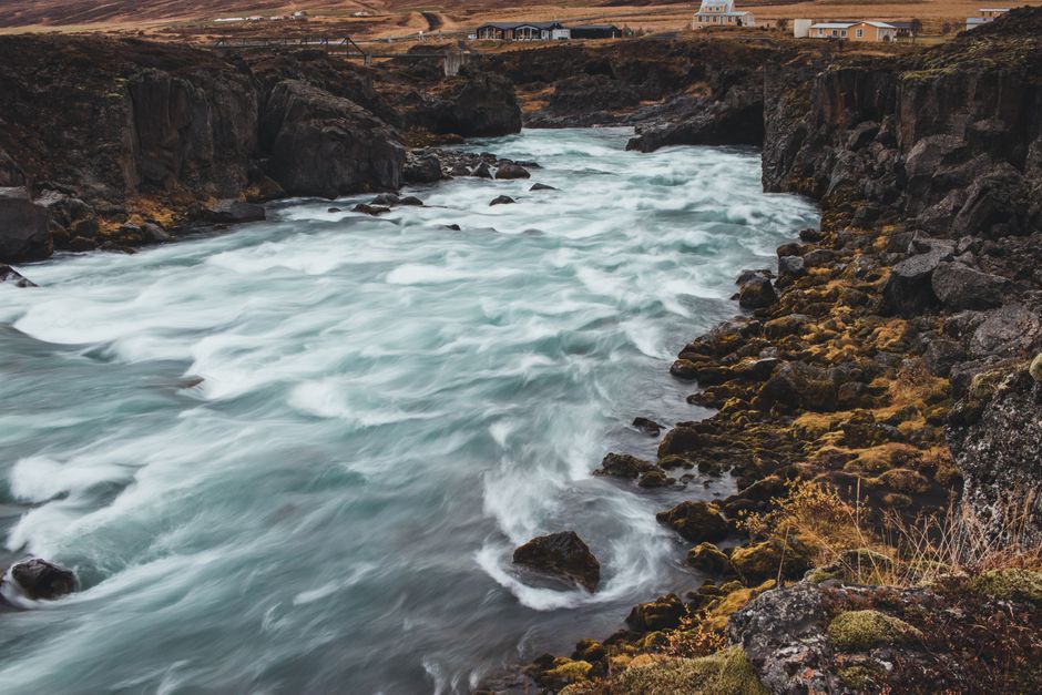 A mesmerizing view of a river in Iceland flowing through rugged, rocky terrain with vibrant moss.