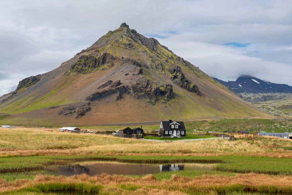 Rustic Icelandic house set against a dramatic mountain backdrop.