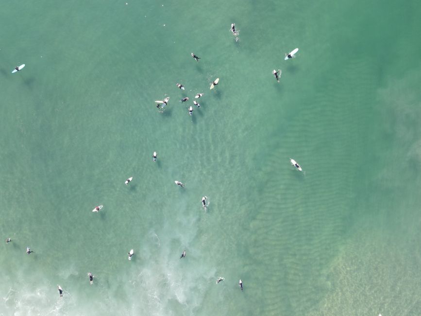 Drone shot showing surfers enjoying a sunny day at Huntington Beach, CA.