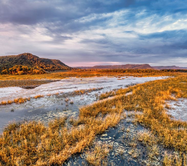 A beautiful wetland landscape in Minneiska, MN at dusk with water, grass, and distant hills.