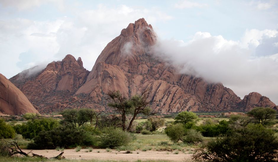 A stunning view of the Spitzkoppe mountains with dramatic clouds in Erongo, Namibia.