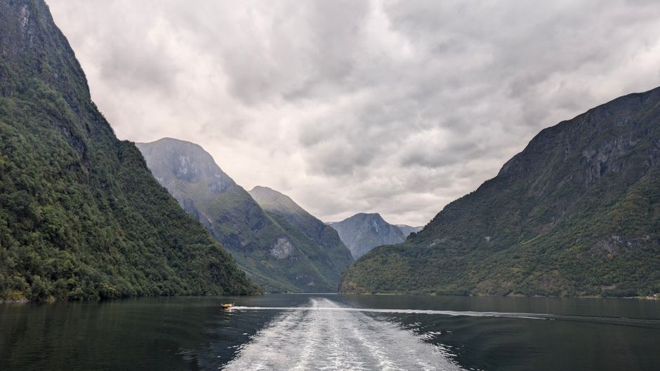 Dramatic fjord landscape with mountains and a water vessel in Bergen, Norway.