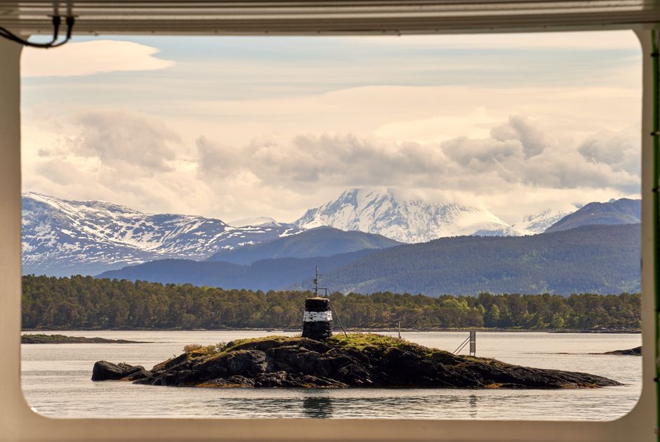 Breathtaking view of snowcapped mountains and a small island seen from a window in Molde, Norway.