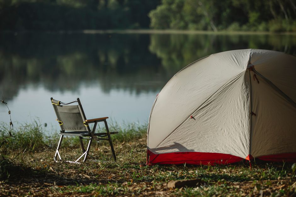 Tent and folding chair beside a lake at a quiet summer campsite