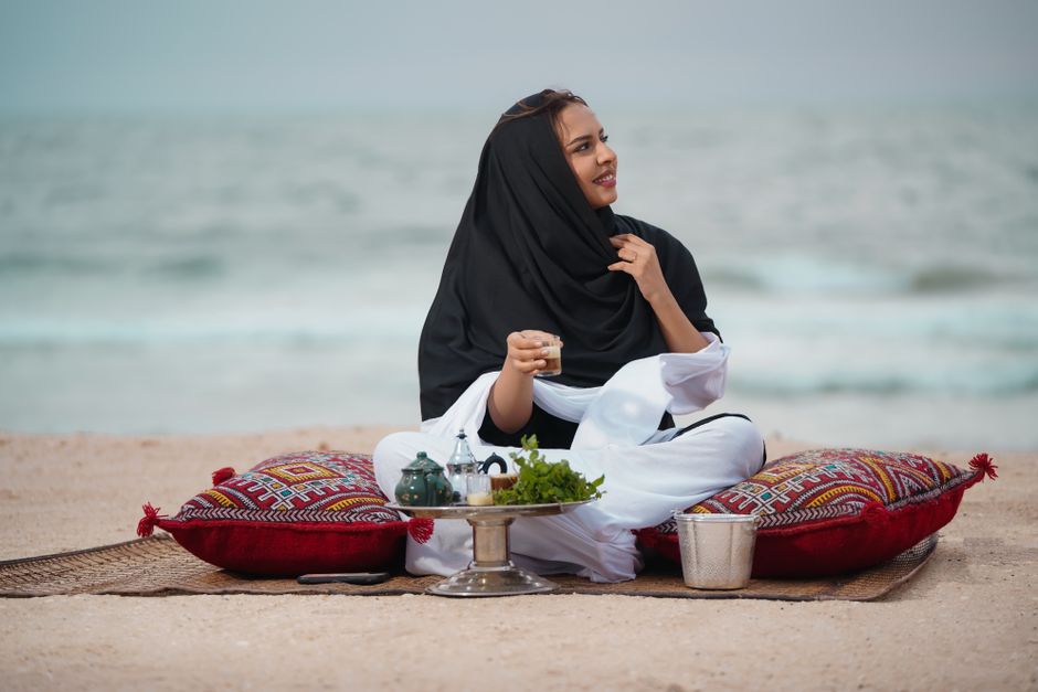 A woman enjoys a serene beach picnic in Nouakchott, capturing a moment of tranquility and cultural richness.